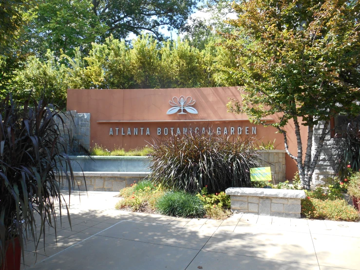 a stone sign sitting in front of a building with trees on each side