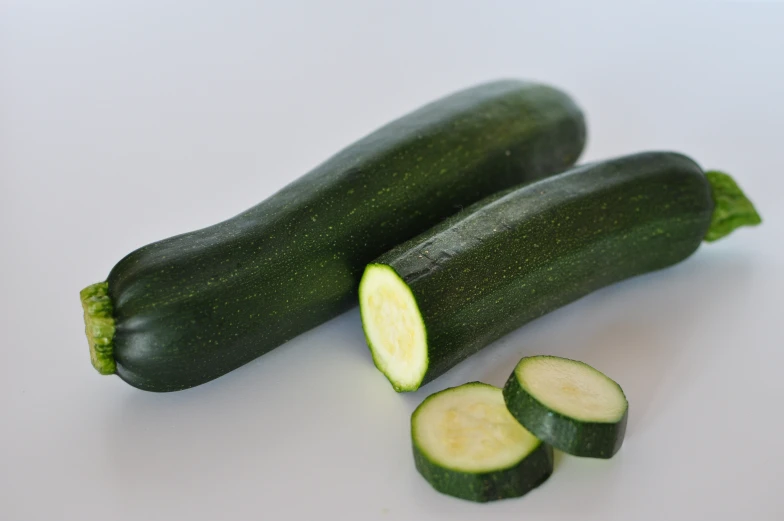 two cucumbers with one cut open on top, sitting side by side