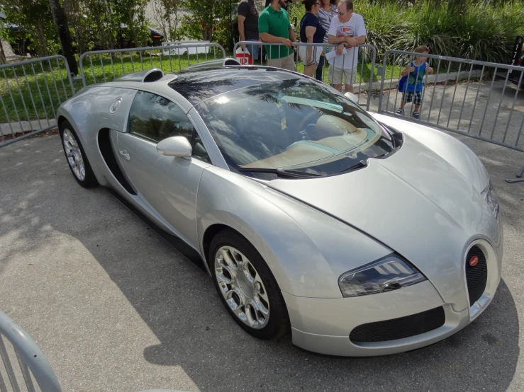 silver sports car sitting in front of a crowd of people