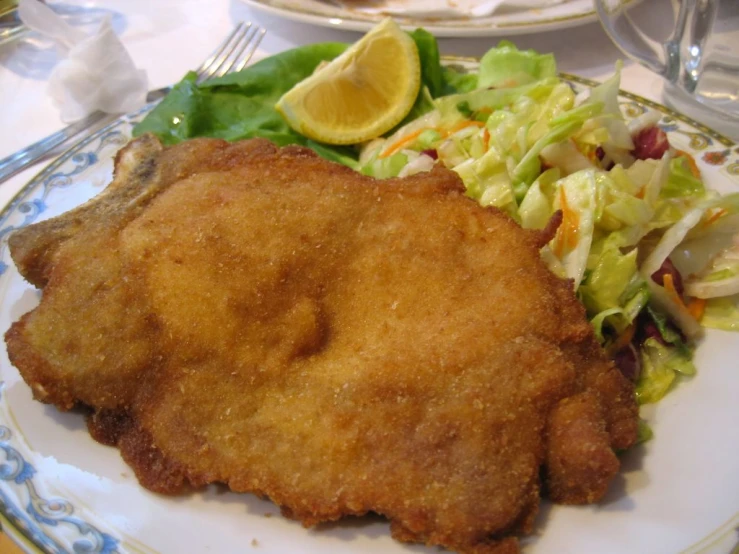 a plate with fried fish and salad and some drink