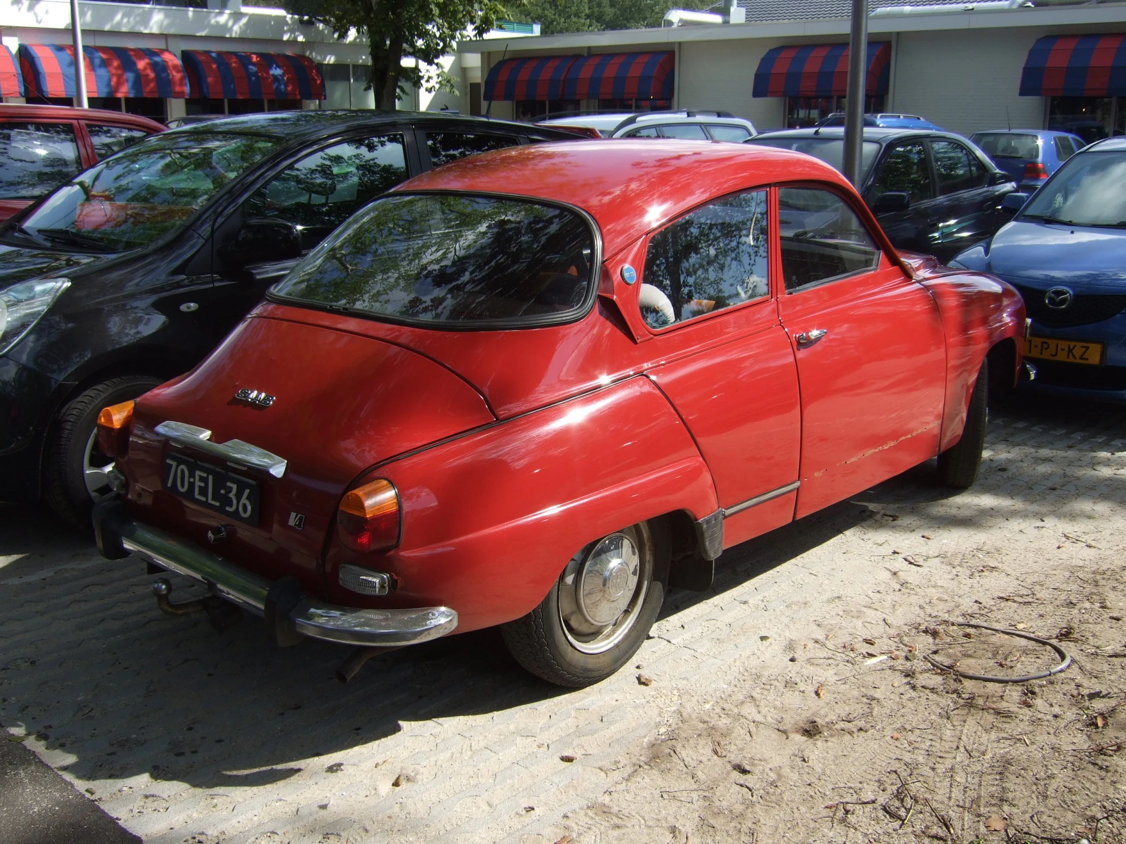 an old red car parked in front of several other cars