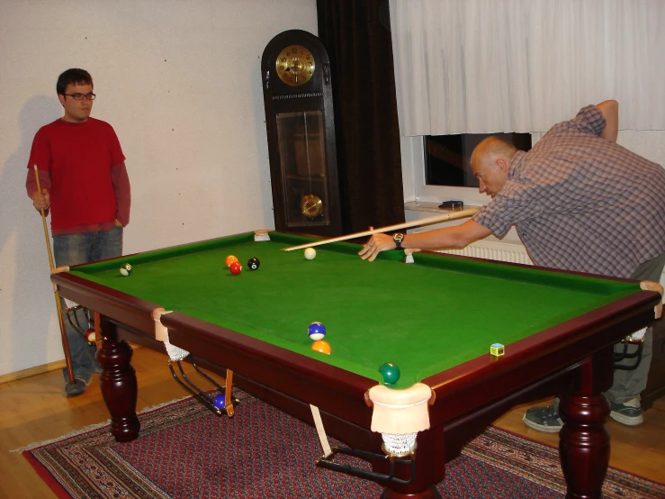 man holding cue in hand over pool table with a billiard