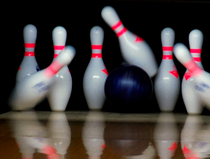 a bowling ball is rolling toward the pins