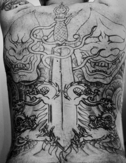 back and shoulder view of a tattooed man with sword