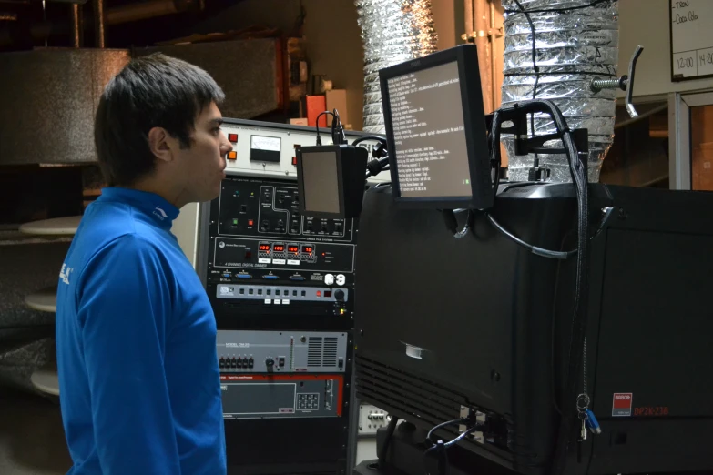 a young man stands in front of a large equipment