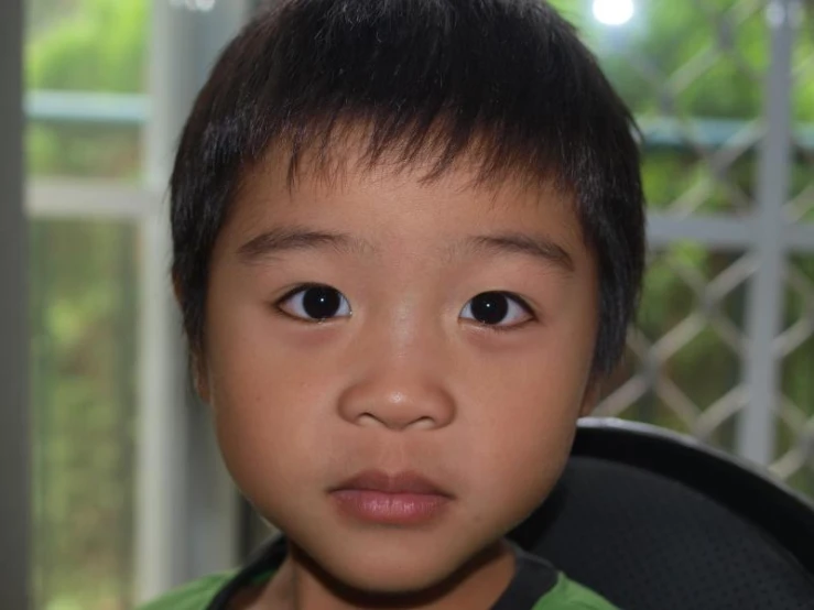an asian boy has a black and green shirt