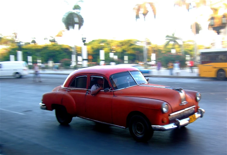 an old red car is seen parked in a parking lot