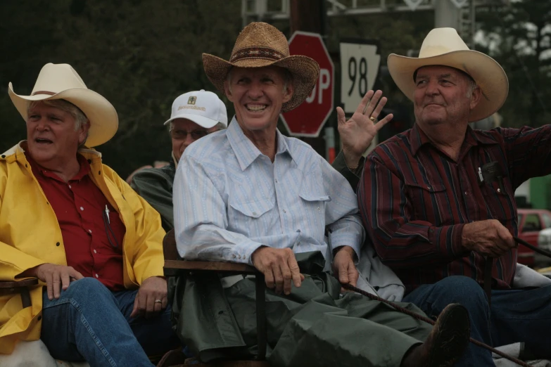 three men sitting next to each other wearing cowboy hats
