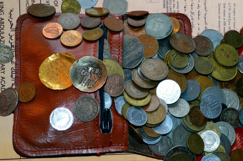 a purse filled with lots of coins sitting on top of a book