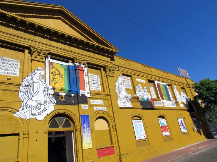 a yellow building with some colorful murals on the wall
