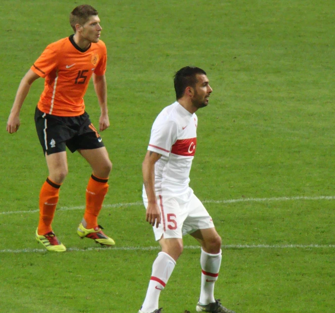 two soccer players in red and white playing ball on grass