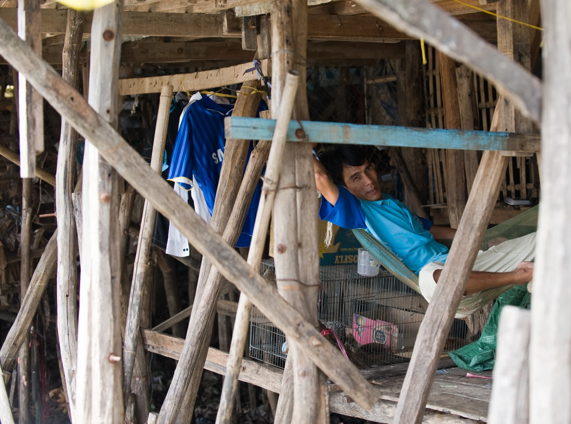 a boy sits on a ladder by himself in a hut with wood beams