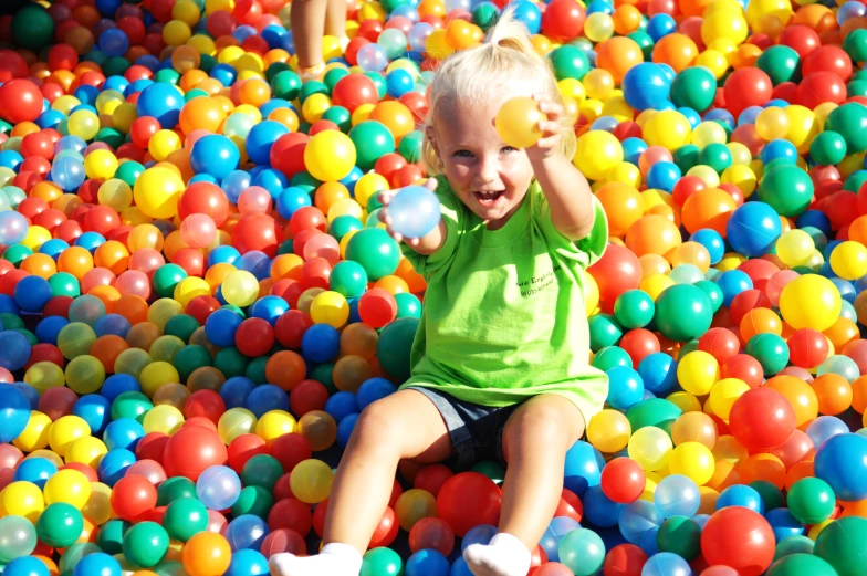 the little boy is playing in the ball pit