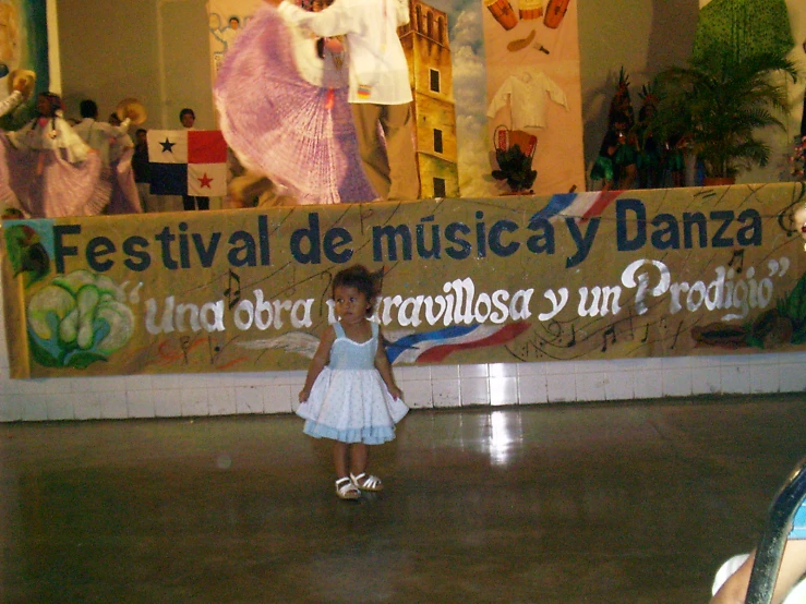 small girl dancing and some large poster behind her