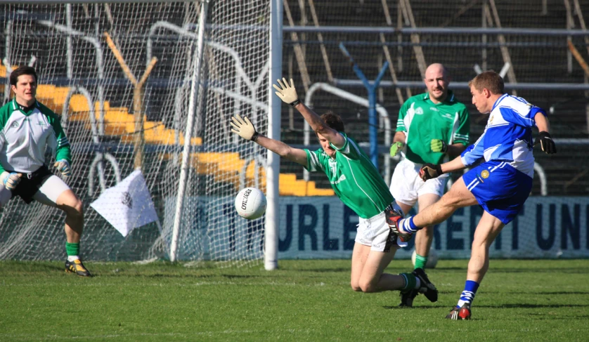 a group of men kicking a soccer ball on top of a grass field