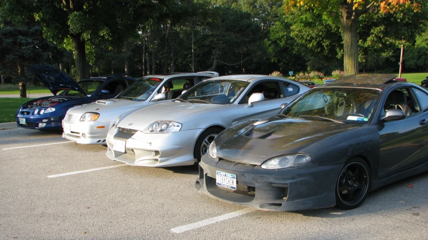 three cars parked in a parking lot with hoods pulled down