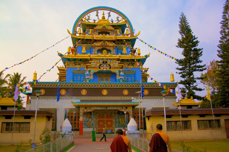 two monks walking away from a colorful pagoda