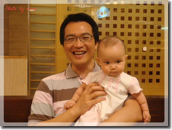 a man holding a baby wearing glasses in a room