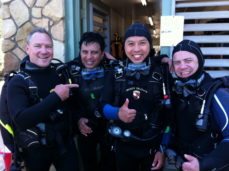 a group of three divers smiling in wet suits