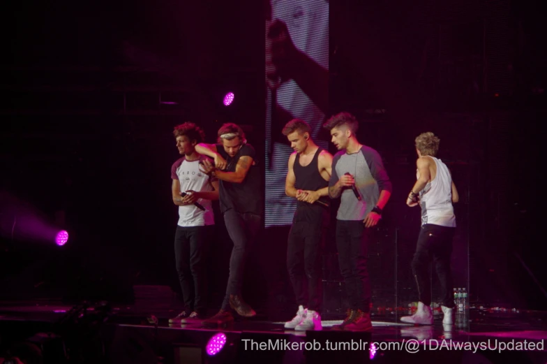 one direction band performing at concert with dark background