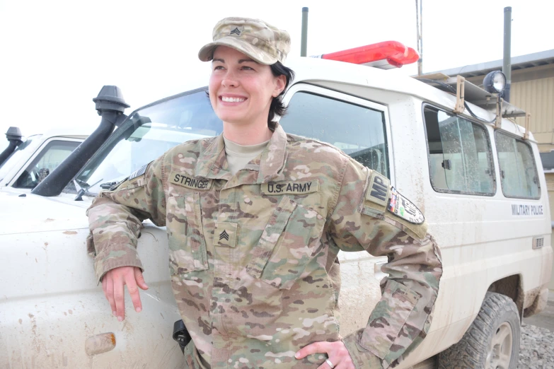 a female soldier posing for the camera near a military truck