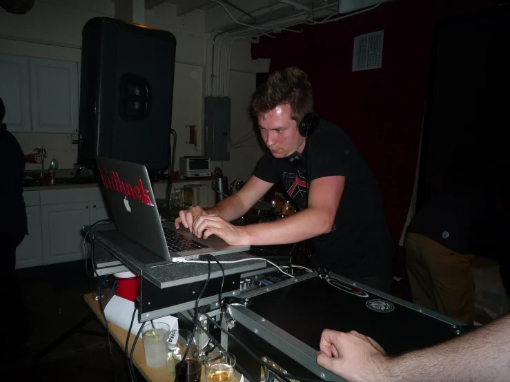 man at party using laptop computer with others nearby