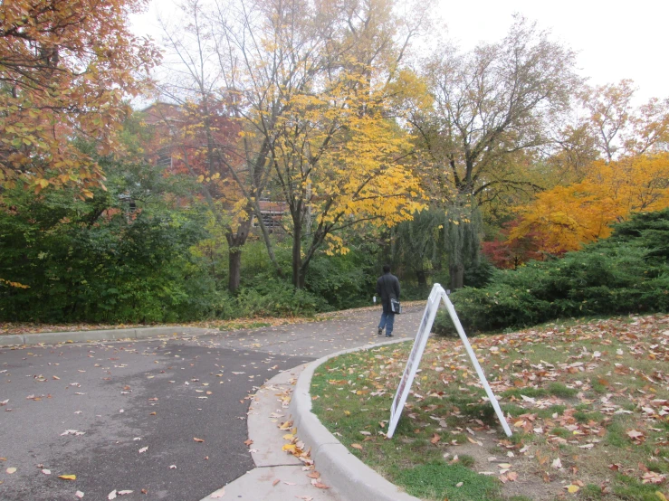 a sign is in front of the road with a man walking by