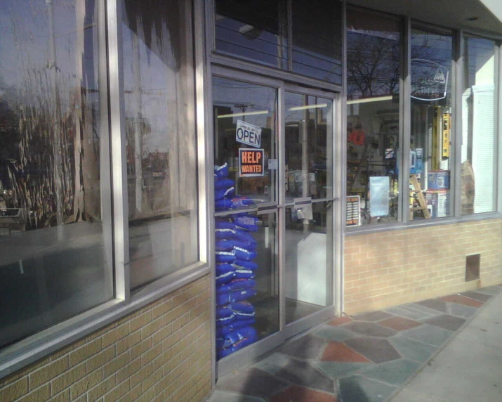 the front entrance to a store with two large blue bags wrapped around the side of the building