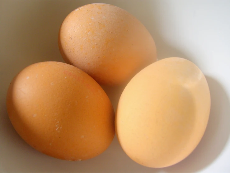 three eggs are in a bowl with some white flecks