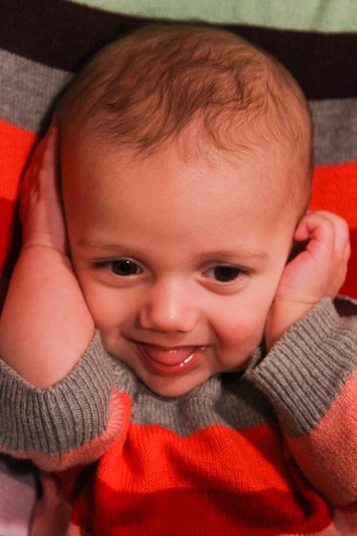 an infant smiling while laying on the floor