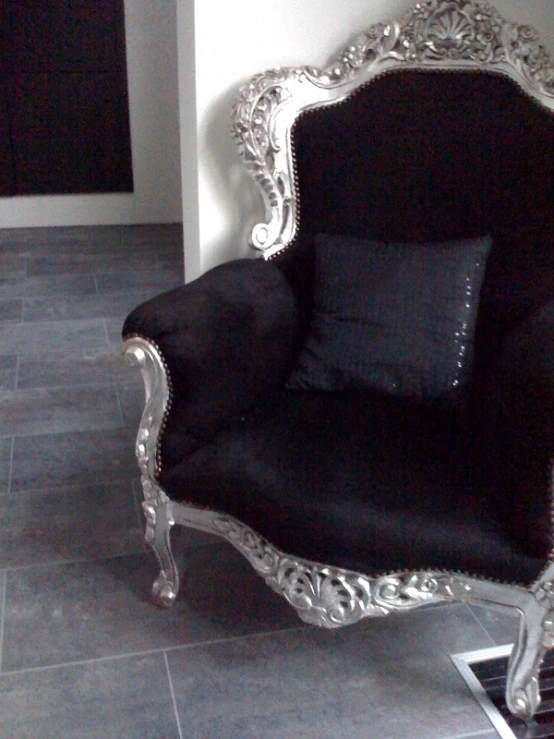 a decorative silver and black chair sitting in the corner of a room