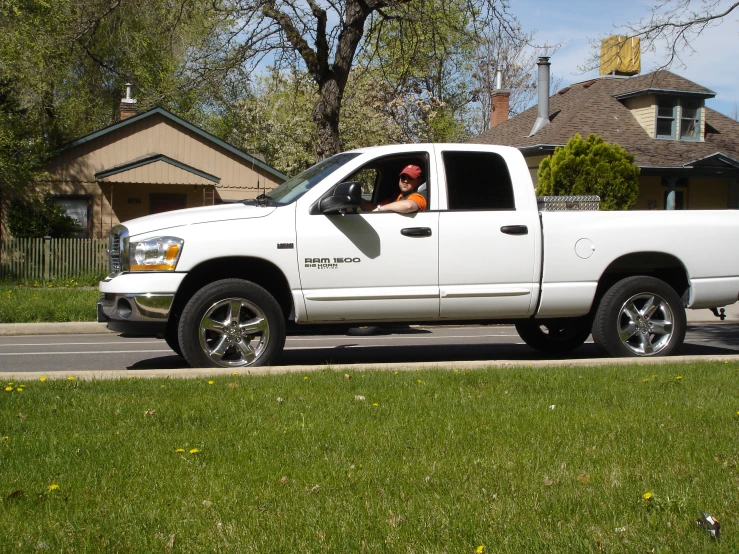 a white truck drives down the street in front of houses