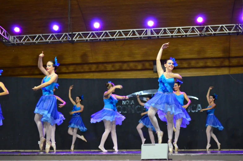 a group of dancers in blue dresses dancing on stage