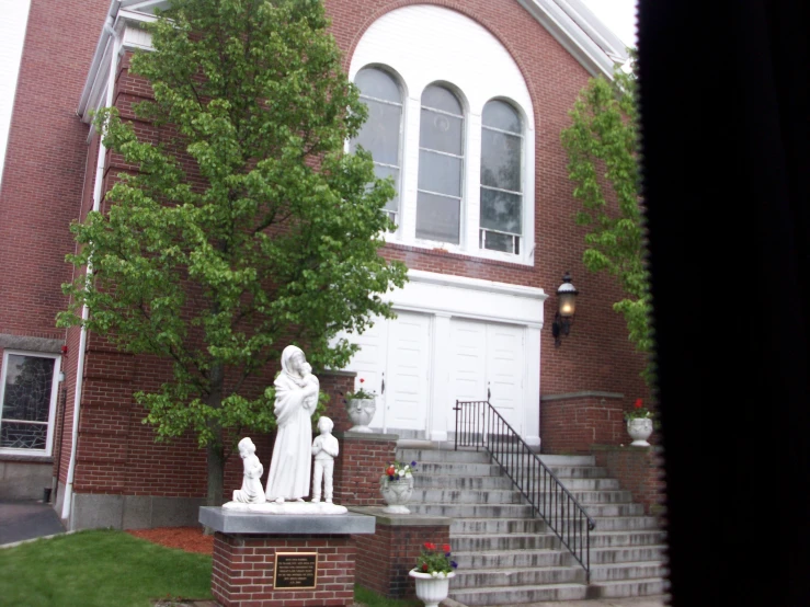 a statue stands outside of an old brick church