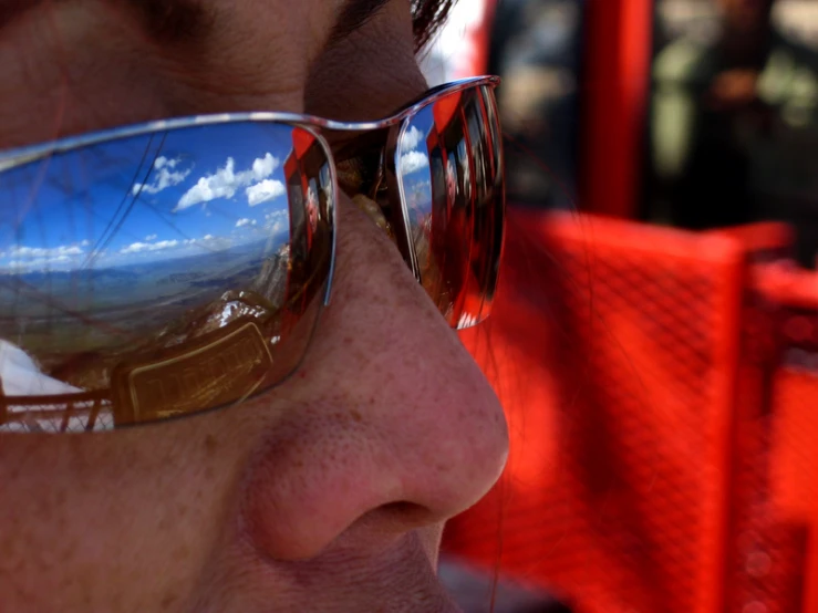 the reflection of clouds in a mirror on a man's sunglasses