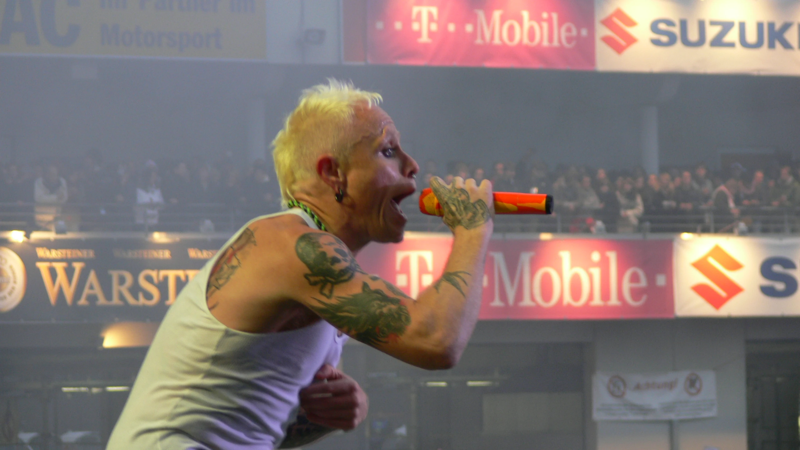 a man wearing white shirt eating and drinking from a bottle