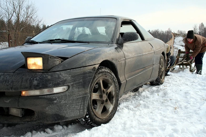 a man repairing a broken down car in the snow