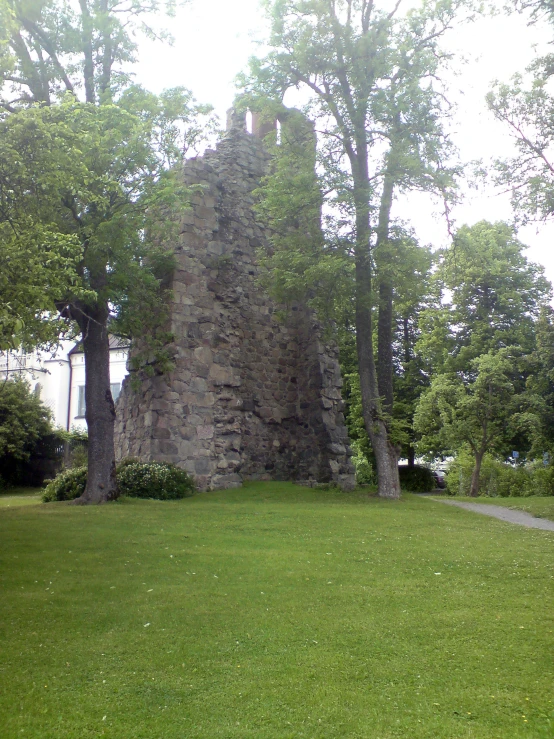 an old tower sitting next to a tree and green field