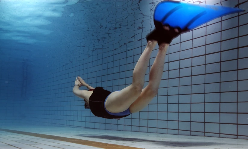 a woman swimming in a pool wearing black swim trunks