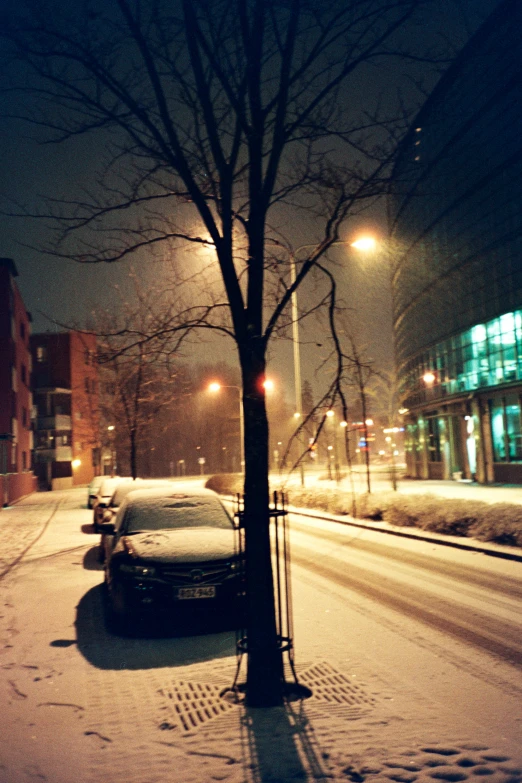 an empty street filled with snow and some cars parked