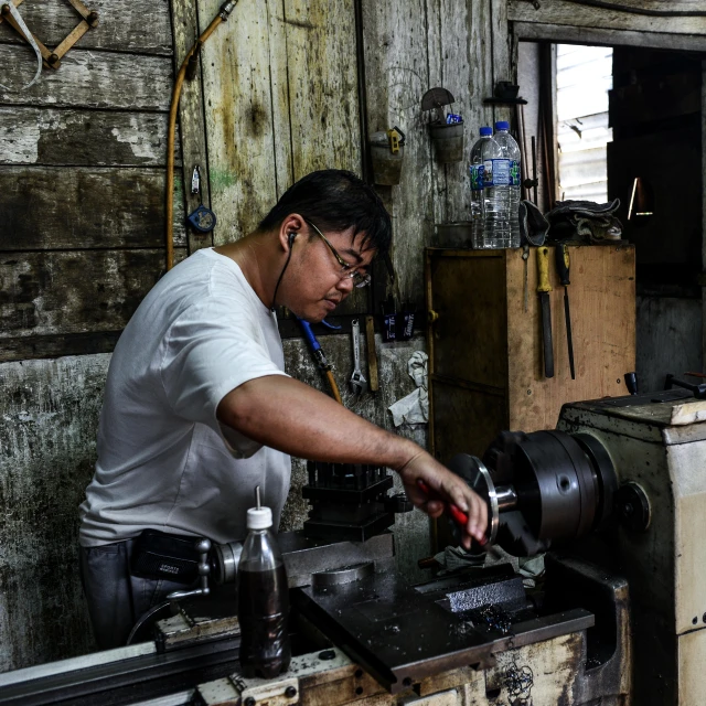 man is drilling metal and working on some type of machinery