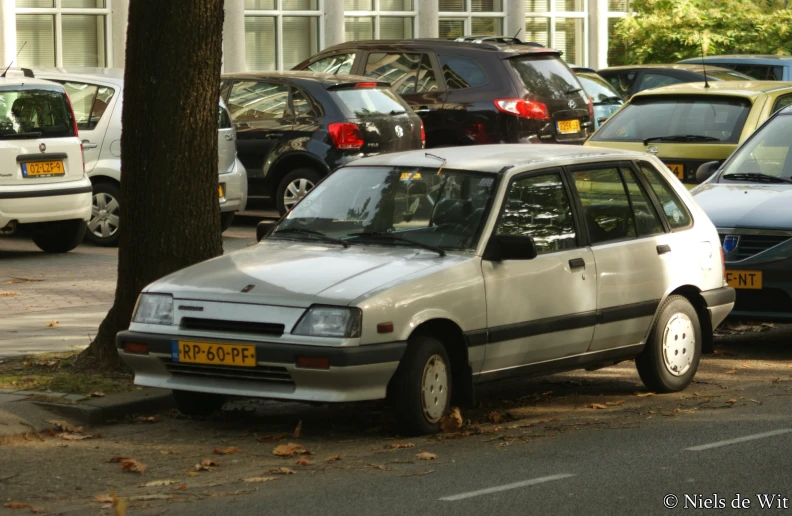 the car is parked next to a tree on a street