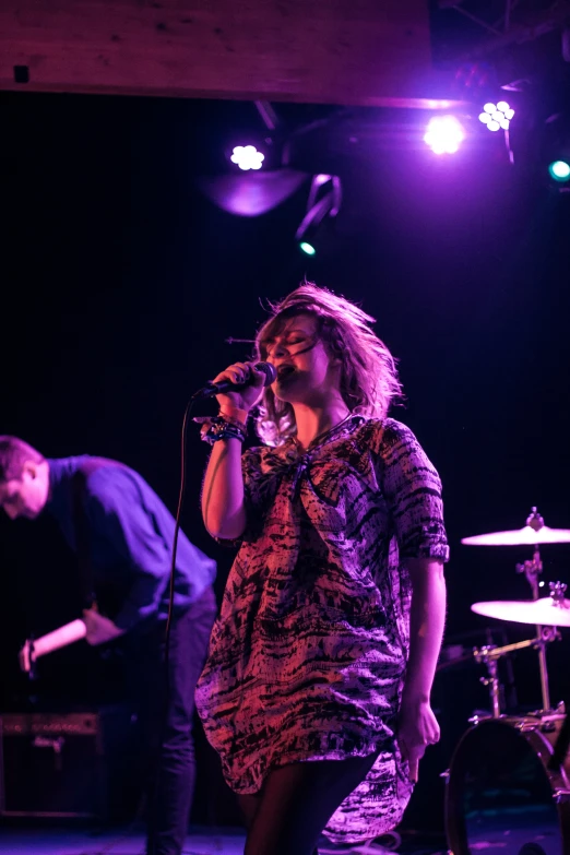 a person on a stage with a microphone and a band behind them