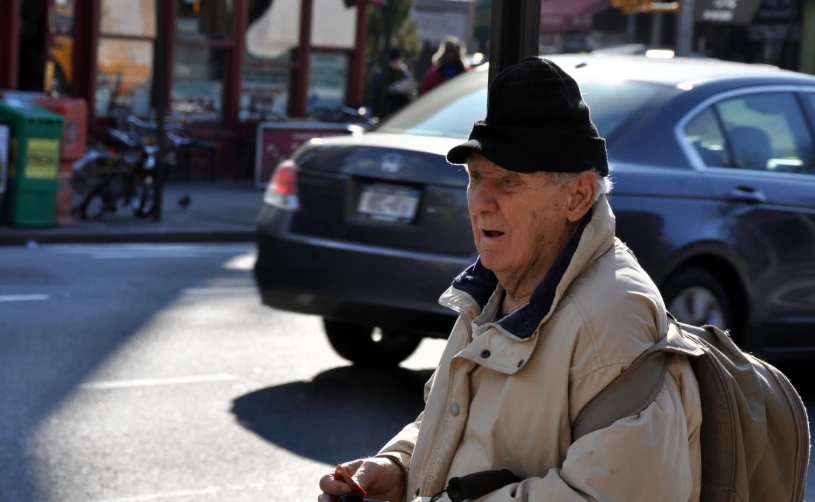 an old man in a black hat on a city street