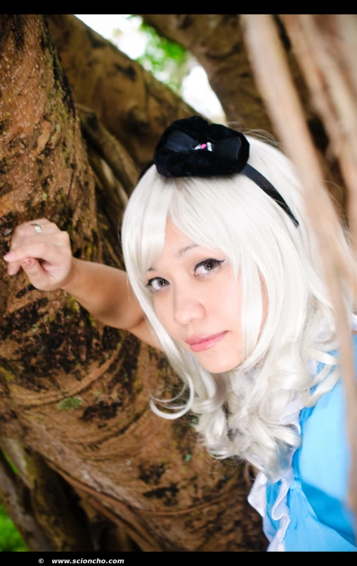 a white haired woman with big  and short hair leaning on a tree