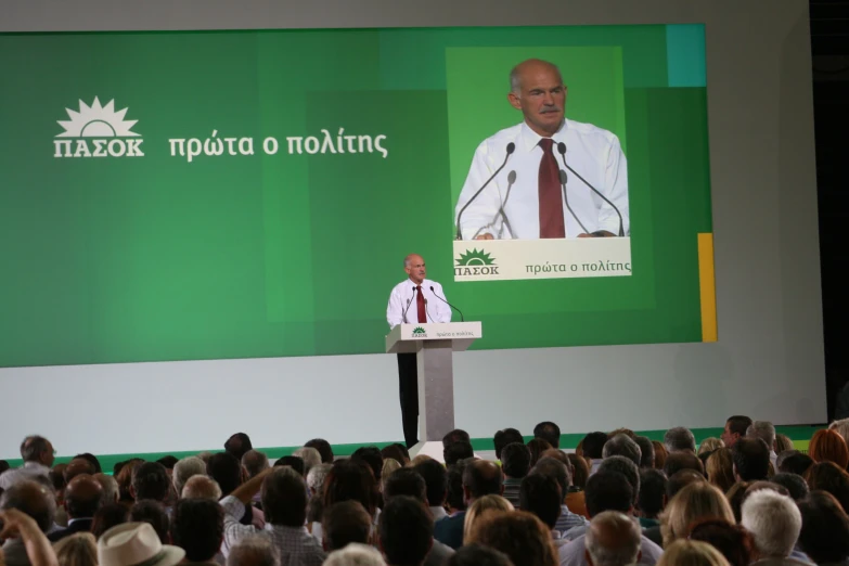 a man standing at a podium addressing to a crowd