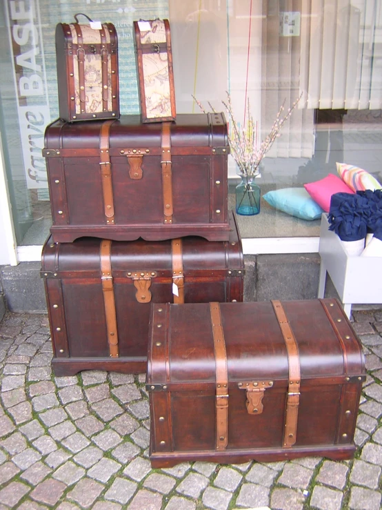 three pieces of brown leather luggage sitting in front of a window