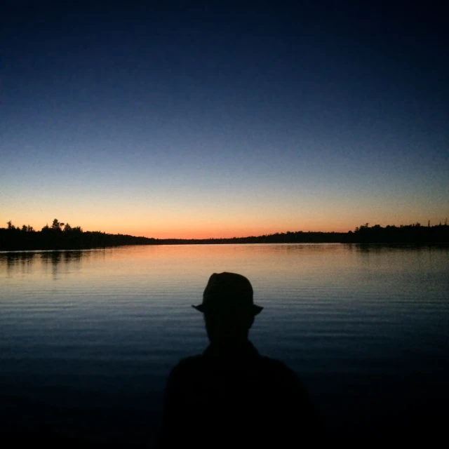 a man looking out over a lake at sunset