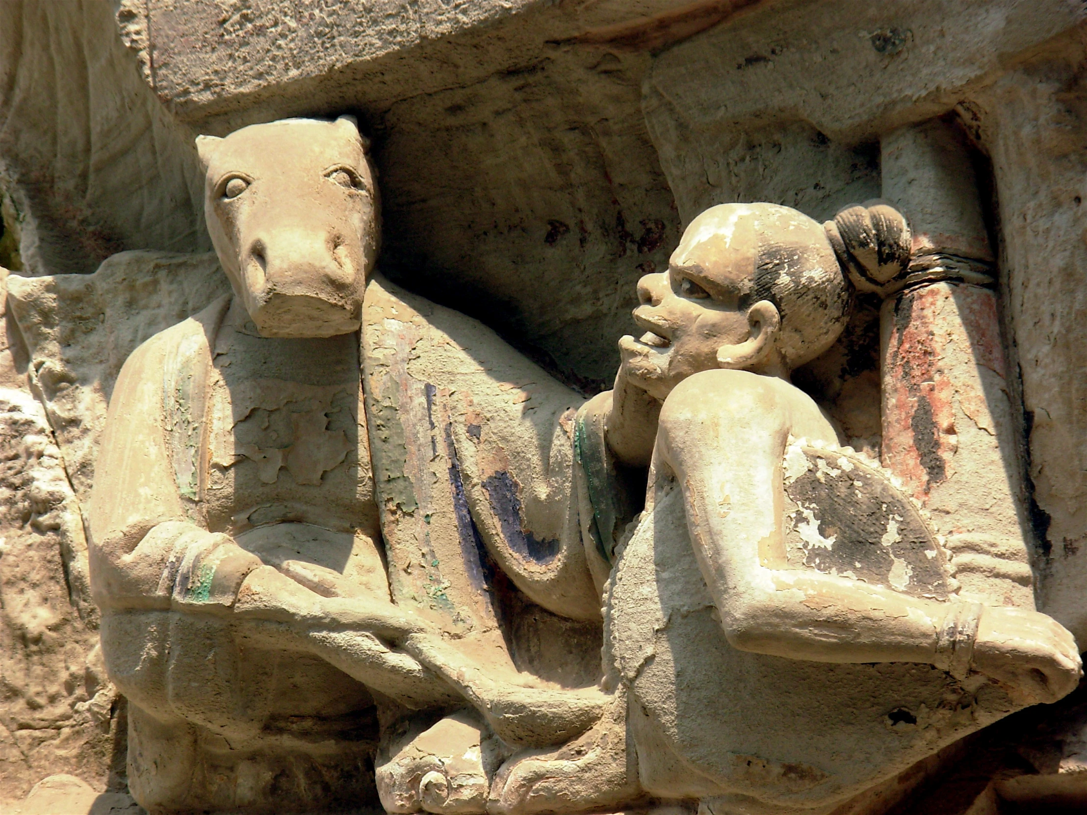 two ancient statues sitting on a bench together