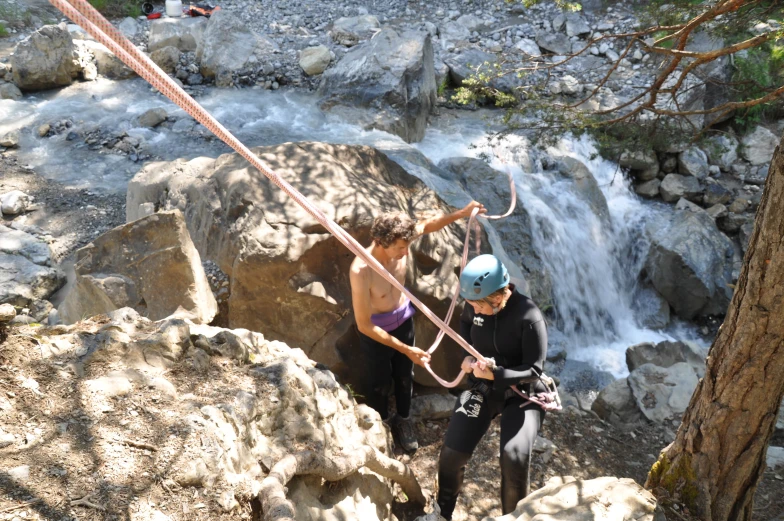 a man and woman are preparing to go down a mountain stream